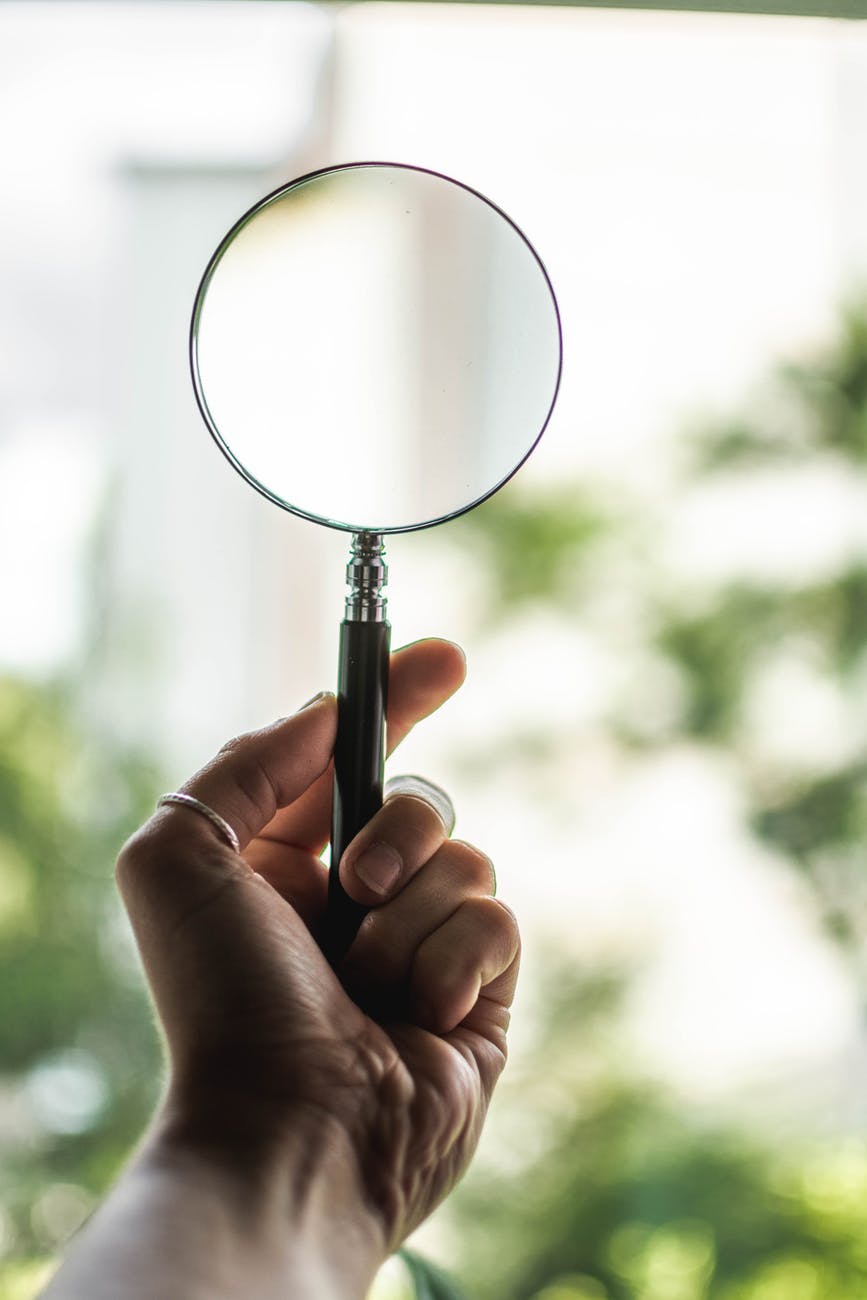 tilt shift lens photography of person holding magnifying glass