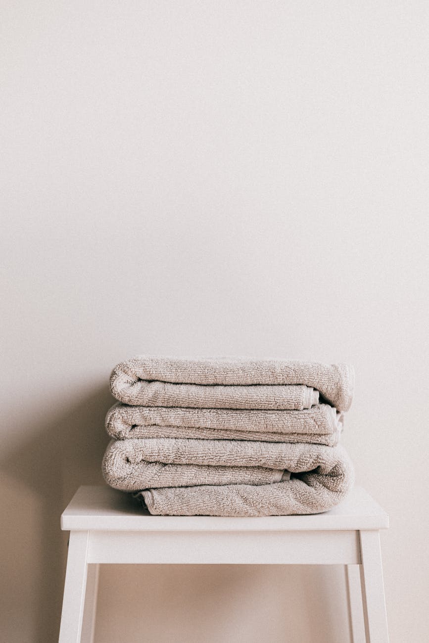stack of fresh gray towels on white stool
