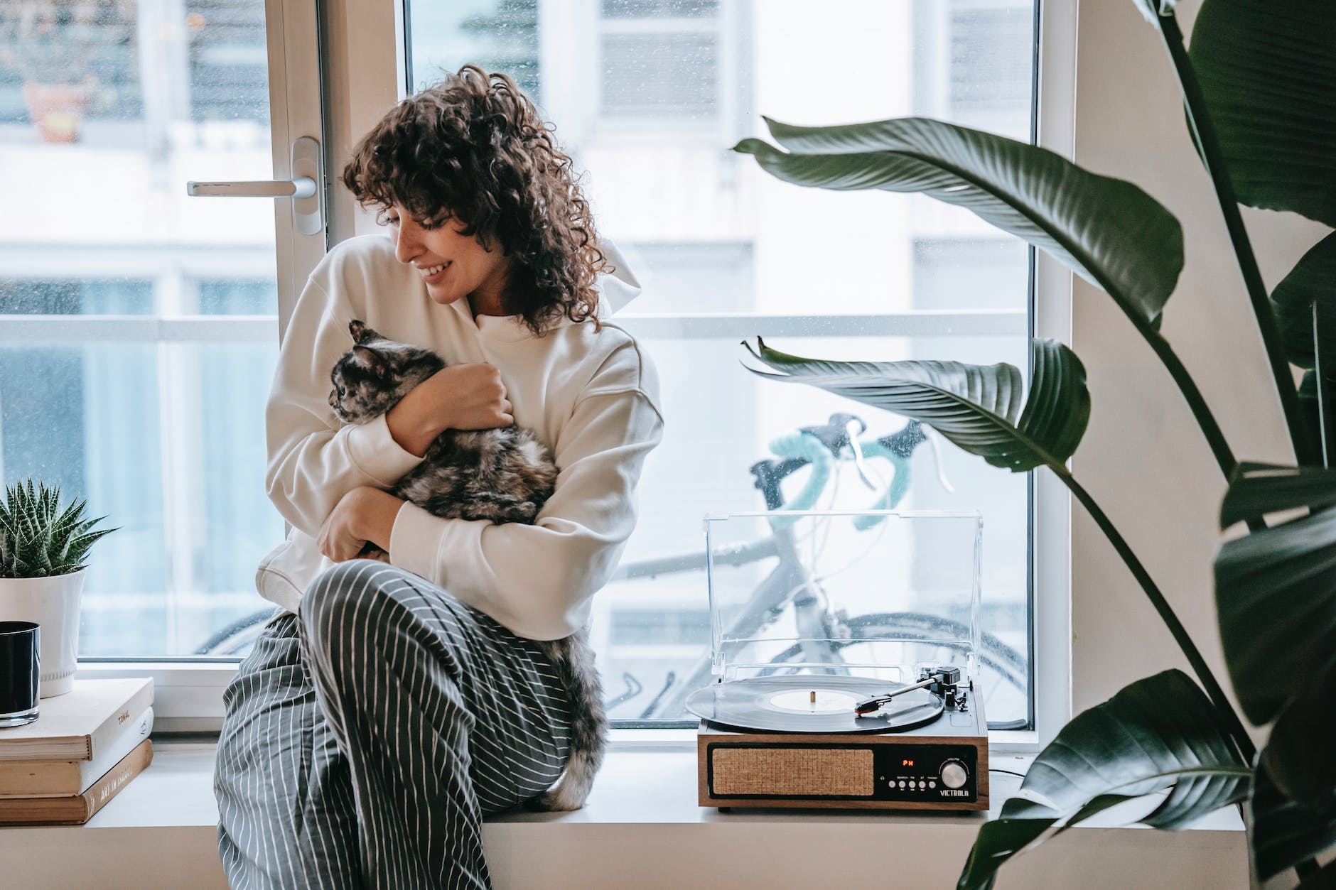 cheerful woman with cat on window with vintage turntable